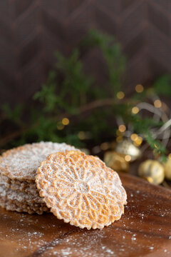Pizzelles Sprinkled with Powdered Sugar on a Wood Tray with Christmas Decor in Background