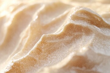 Obraz premium Close-up view of a textured, sandy beige surface resembling dunes or a creamy substance.
