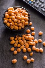 Peanuts in a crispy crust in bowl on black table.
