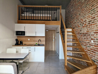 kitchen and living area with wooden staircase and cozy loft sleeping area in a contemporary urban apartment