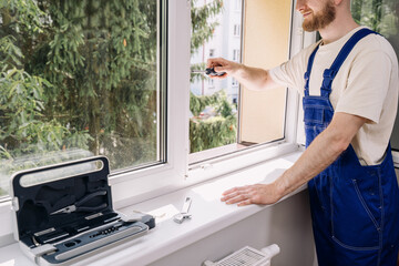 Repairman installs an energy-efficient PVC window frame in a residential apartment