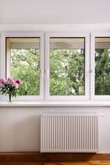 Modern PVC window frame in a bright residential room with fresh flowers