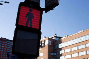 Red pedestrian traffic signal with digital elements in urban setting, integration of technology in...