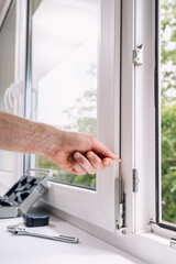 Repairman installs PVC window for improved energy efficiency in home