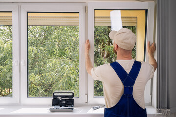 A skilled repairman is installing a new PVC window frame in a residential building