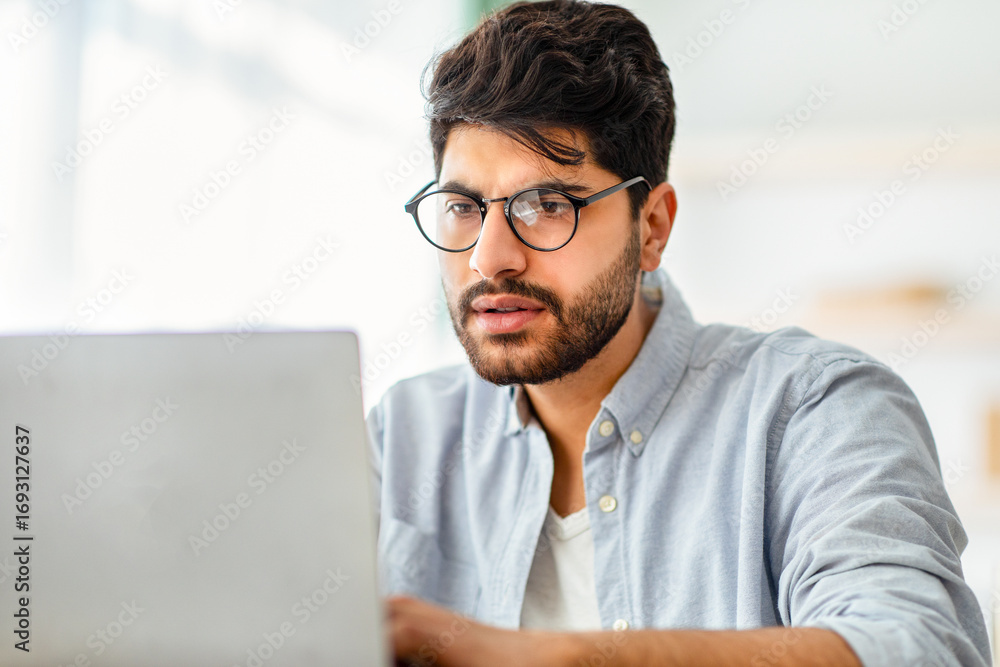 Poster remote work concept. concentrated arabic male freelancer working on laptop, typing on computer keybo