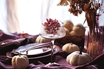 A top-down view of an elegant fall table setting with pumpkins, decorative plates, a linen napkin...