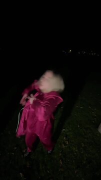 Young blonde woman dancing waacking in a park at night