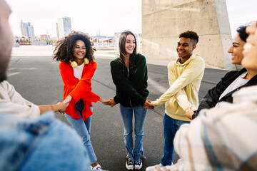 Young diverse friends holding hands outdoors, symbolizing trust and connection. Student community...