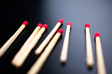 Close-up of wooden matches with red tips scattered on a black background, highlighting contrast between natural wood texture and vibrant striking heads.