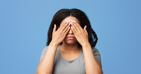 See no evil concept. Young unrecognizable african american woman covering eyes with hands, standing...