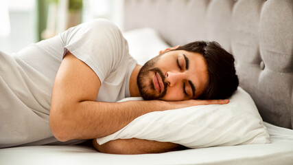 Comfortable sleep. Millennial arab man sleeping peacefully and see sweet dreams, lying in comfy bed...