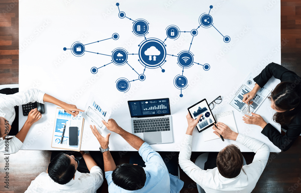 Poster a top-down view of a business team collaborating on cloud computing strategies, using laptops and ch