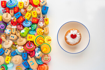 Hanukkah dreidels and traditional donut Sufganiyah for Jewish holiday on white background. Hebrew...