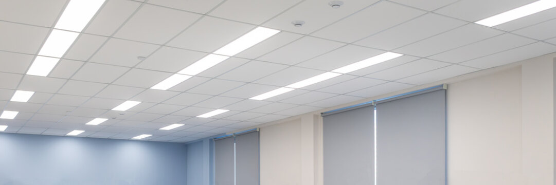 Modern office ceiling with recessed LED lighting and suspended tiles. Clean, functional interior design for corporate spaces. Banner, photo