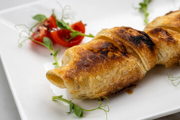 Golden baked pastry roll with cheese, served with cherry tomatoes and microgreens