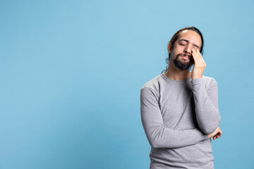 Exhausted young adult falling asleep while standing in front of camera, feeling very tired and...
