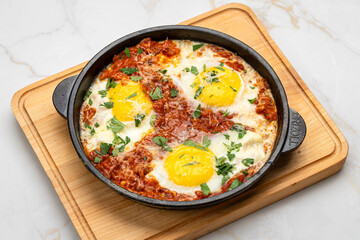 Shakshuka in cast iron skillet with tomatoes, herbs, and sunny-side-up eggs