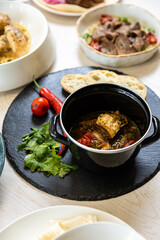 Traditional Georgian khashlama stew with beef, vegetables, herbs and bread on slate plate