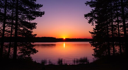 Fototapeta premium Sunset Over Calm Lake Surrounded by Pine Trees.