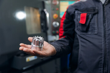 Male engineer holding metal component in industrial factory setting