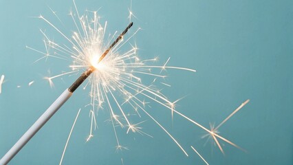 Closeup of a single sparkler burning against a blue background, creating a festive and celebratory atmosphere with bright sparks and a sense of joy