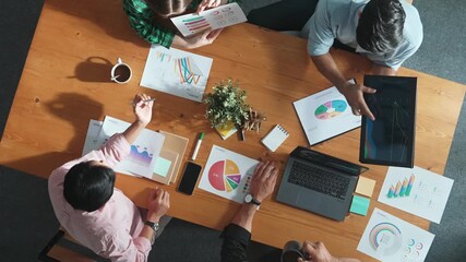 Top down aerial view of business man pointing and presenting at financial chart while diverse team discussing about stock market statistic at meeting table with laptop and graph document. Convocation. - Powered by Adobe