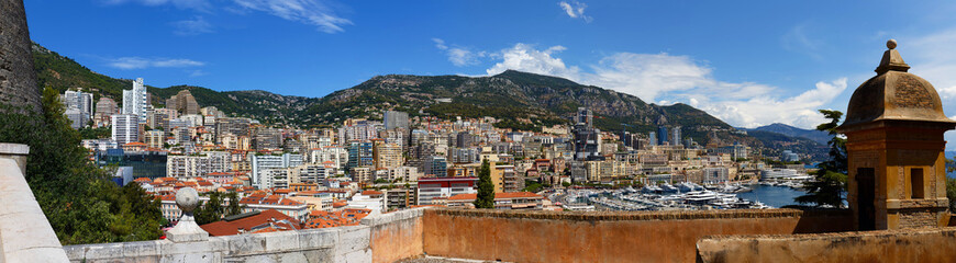 Elevated view of Monaco cityscape with red rooftops, layered high-rises, and lush green hills. Scenic urban landscape of the Principality, blending modern architecture with Mediterranean charm.
