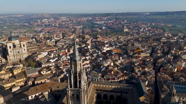 Bright aerial drone fly-past shot along the towering Gothic spire of the Primate Cathedral of Saint Mary of Toledo, Spain.