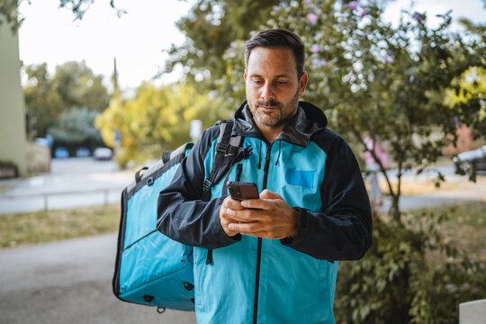 Delivery man using smartphone app checking next delivery address in the city