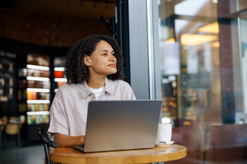 A young woman sits in a caf, focused on her laptop, enjoying a productive moment