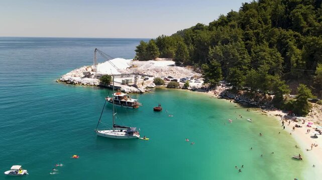 Yachts in sea on Porto Vathy beach, Thassos Island, Greece. Amazing beach with clear blue water. Aerial panoramic drone view from above, top view from drone. Summer holidays Europe
