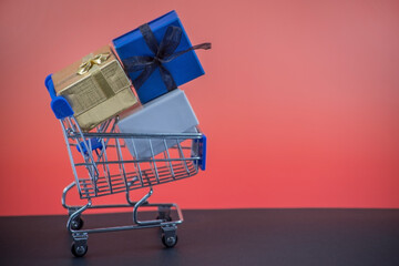 Side view shopping cart with three gift boxes on black and red background
