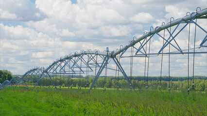 The Efficient Irrigation System Spreading Over a Vast Green Field Beneath a Clear Blue Sky