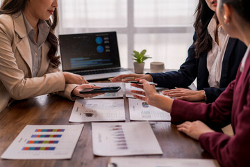 Businesswomen team discussing and analyzing financial charts using mobile phone and laptop