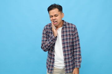 Young asian man isolated on blue background, touching his face with expression of suffering from...
