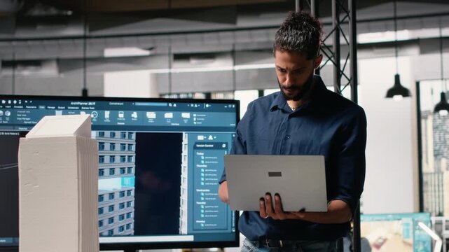 Male developer evaluating architectural 3D models and plans to find measurements and zoning regulations, collecting construction site and layout details in the office. Camera B.