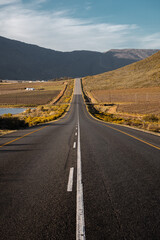 Straight road through mountain valley at sunset