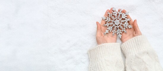 Hands with decorative snowflake on snowy background with space for text