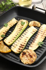Delicious grilled courgette slices with garlic, lemon and parsley in pan on grey table, closeup