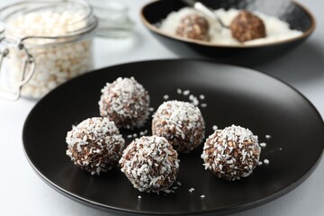 Tasty chocolate candies with coconut flakes on white table, closeup