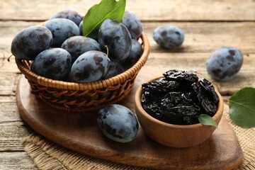 Dried prunes and fresh plums on wooden table, closeup