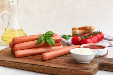 Board of tasty sausages with basil and tomatoes on table