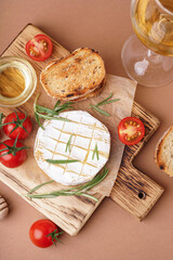 Wooden board with tasty baked Camembert cheese on brown background
