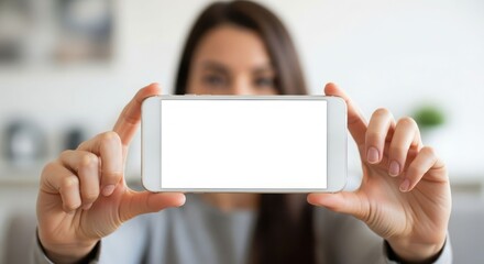 A woman holds a white smartphone horizontally, displaying a blank screen, with her face blurred in the background.