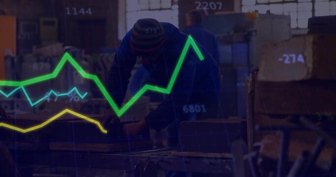 Front worker wearing beanie and coveralls inspecting workbench in workshop with financial overlay