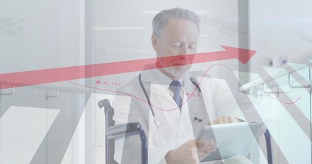 Senior doctor in white coat analyzing tablet data in hospital hall with wheelchair and stethoscope