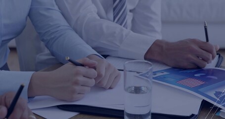 Professionals in dress shirts and tie reviewing chart while writing with pencil on conference table