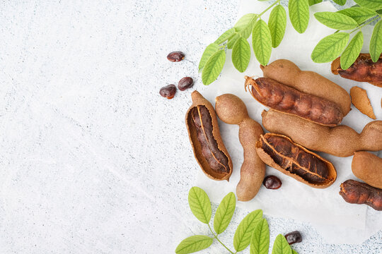 Tasty tamarinds, leaves and seeds on white background