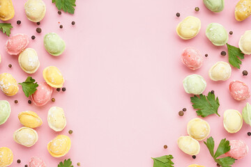 Colorful raw dumplings with peppercorn and parsley on pink background